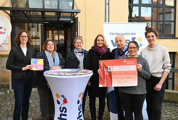 Zu sehen sind 7 Personen, eine hält einen Spendenscheck für "Inklusion" hoch.