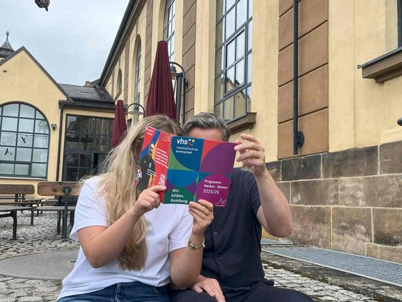 Zu sehen sind 2 Personen, die im neuen Programmheft blättern